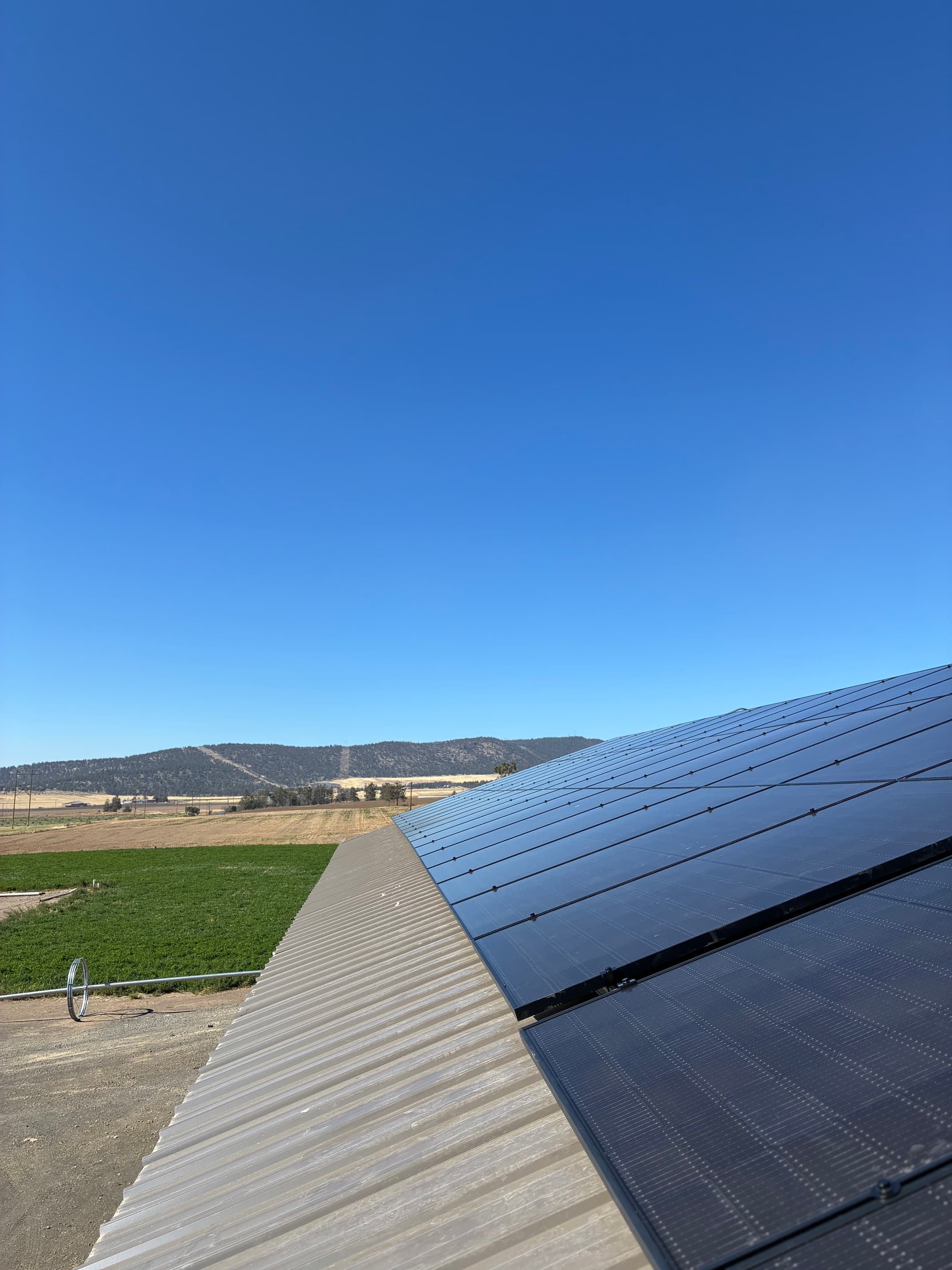 Solar panels on a rural Klamath County roof beneath a clear blue sky.