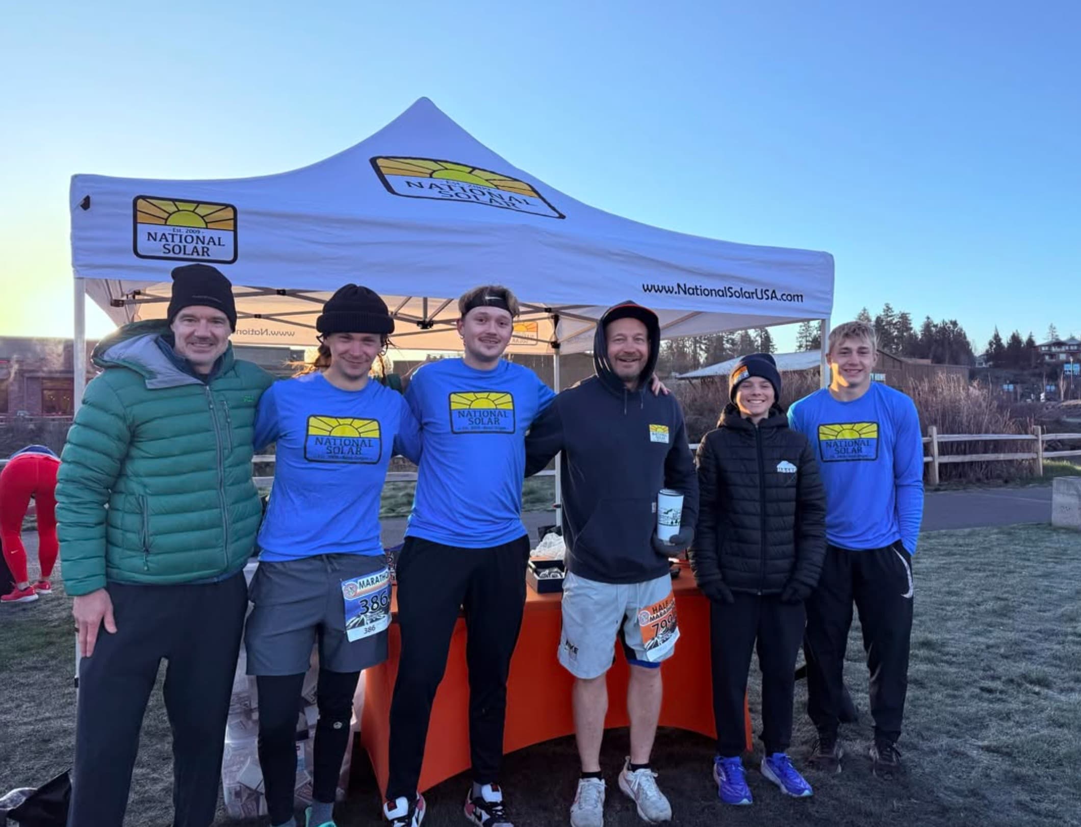 National Solar team members and runners pose together beneath the National Solar race-day tent.